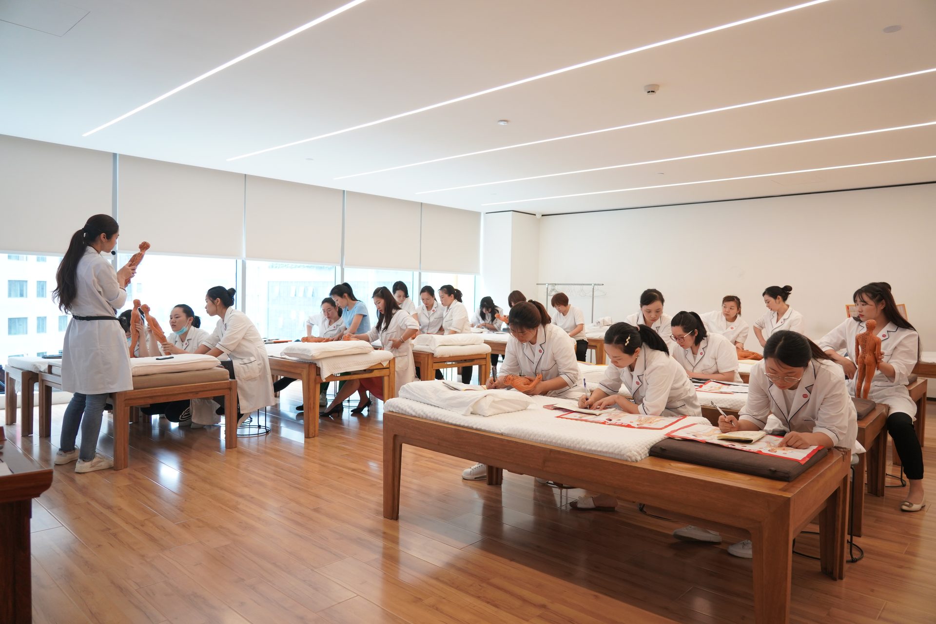 常乐职业技能培训学校推拿实训教室全景，学员在按摩床旁实操
