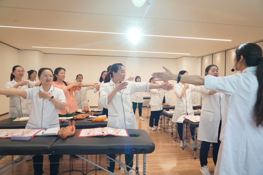 学员在实训课堂集体练习推拿手法与站姿，教师现场带练